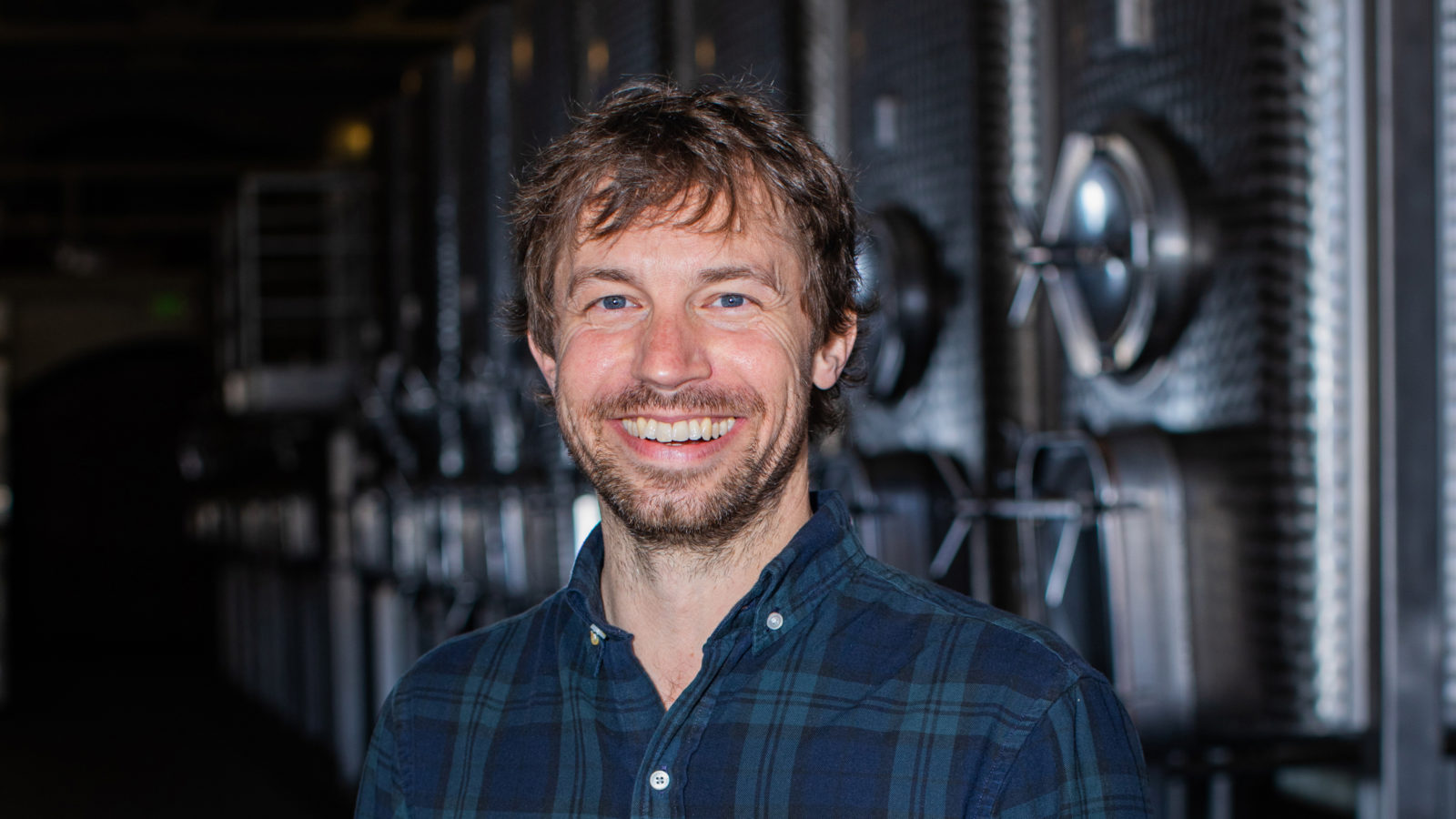 Jeff Crawford in front of fermentation tanks plaid